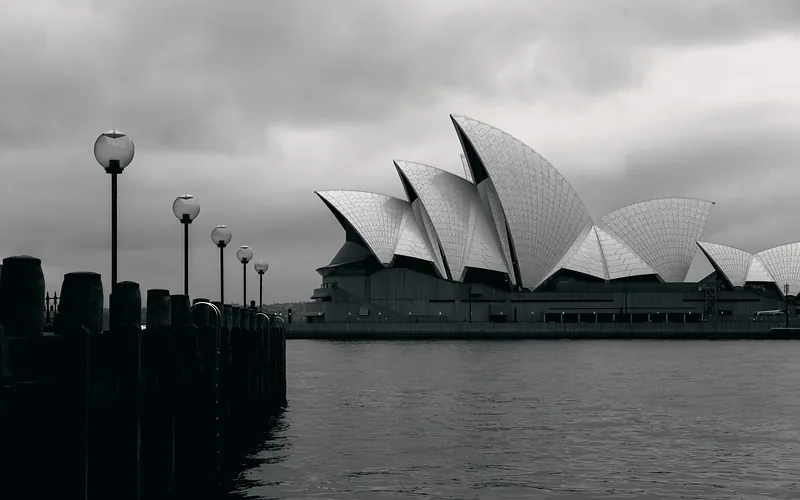Black and white geometrical facade of modern Sydney Opera House in expressionism style located on embankment on cloudy day