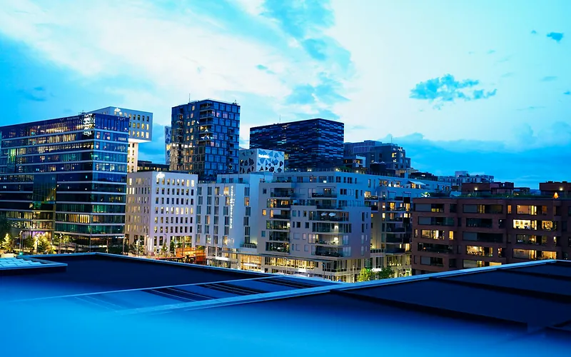 Illuminated modern buildings in Oslo's downtown at twilight, showcasing architecture