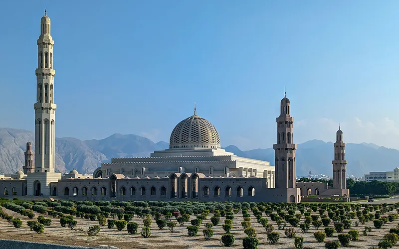 Sultan Qaboos Grand Mosque with its striking minarets against a clear blue sky in Muscat, Oman