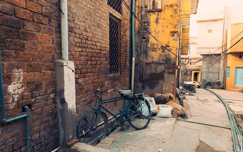 Old bicycle leaning on a timeworn brick wall in a quiet Chiniot alley, Punjab, Pakistan