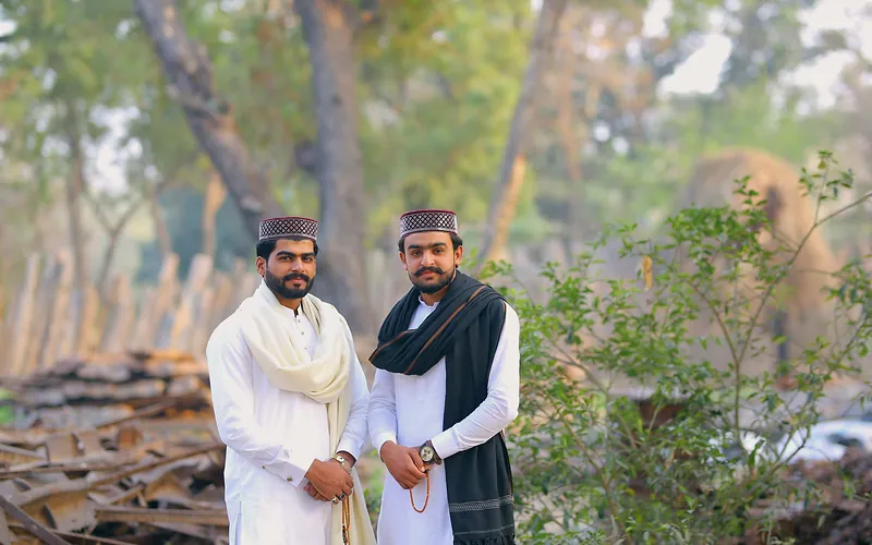 Two men in traditional attire standing in a forested area in Kasur, Punjab