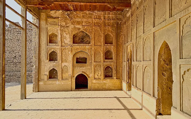 Sunlit interior of Kot Diji Fort showcasing detailed carved architecture in Khairpur, Pakistan