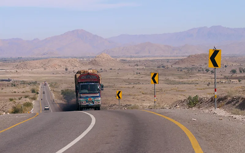 Colorful truck navigating a winding road in the arid mountains of Khuzdar, Pakistan