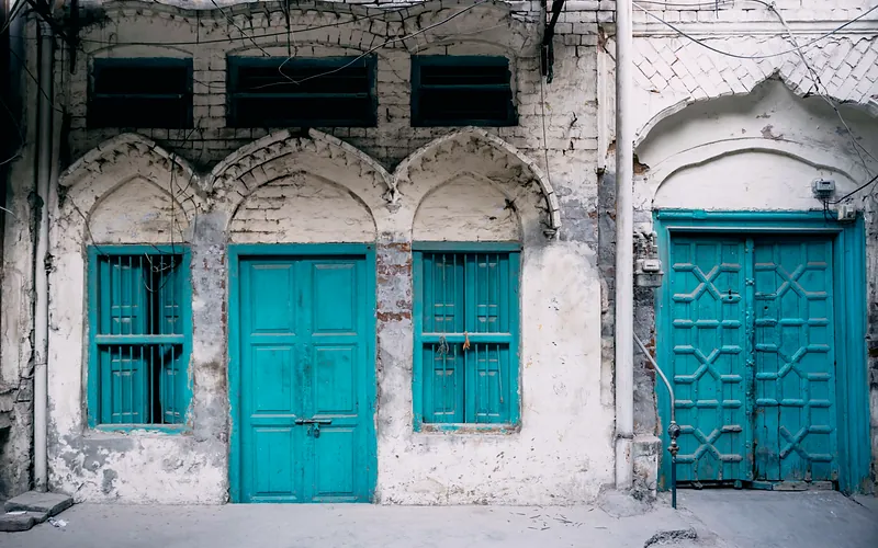 Close-up of vintage turquoise wooden doors on a historical building facade in Faisalabad, Pakistan, Punjab