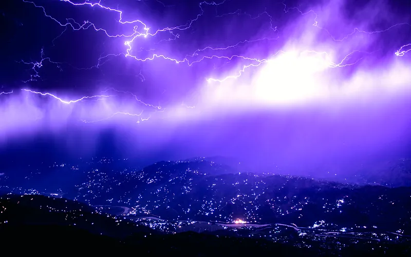 Captivating lightning storm over Muzaffarabad with a vivid purple sky, lighting up the mountains at night