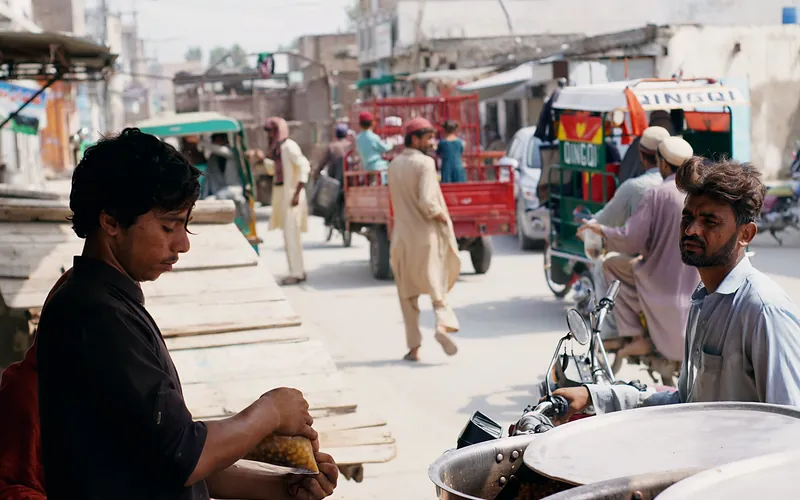 Street vendor selling food in bustling Nowshera, Pakistan. Urban life depicted with locals