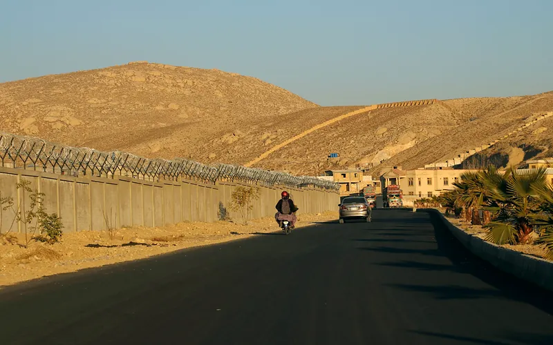 A motorcyclist rides along a road in Quetta, surrounded by desert landscape and walls