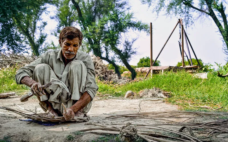 Elderly man working skillfully with wooden sticks in a park setting in Mian Channu, Punjab, Pakistan, Punjab